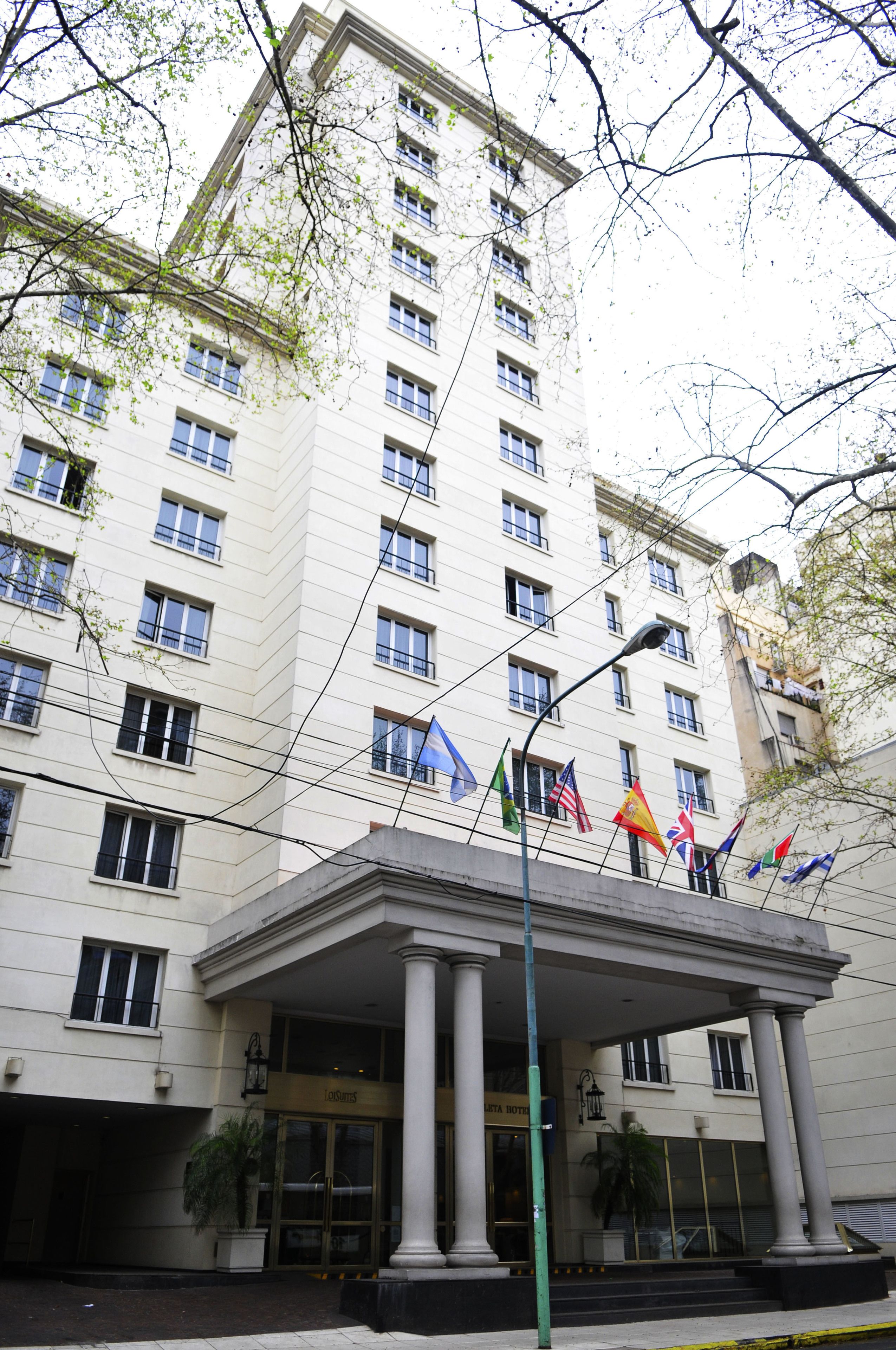 A multi-story hotel with a central entrance featuring a portico supported by columns.