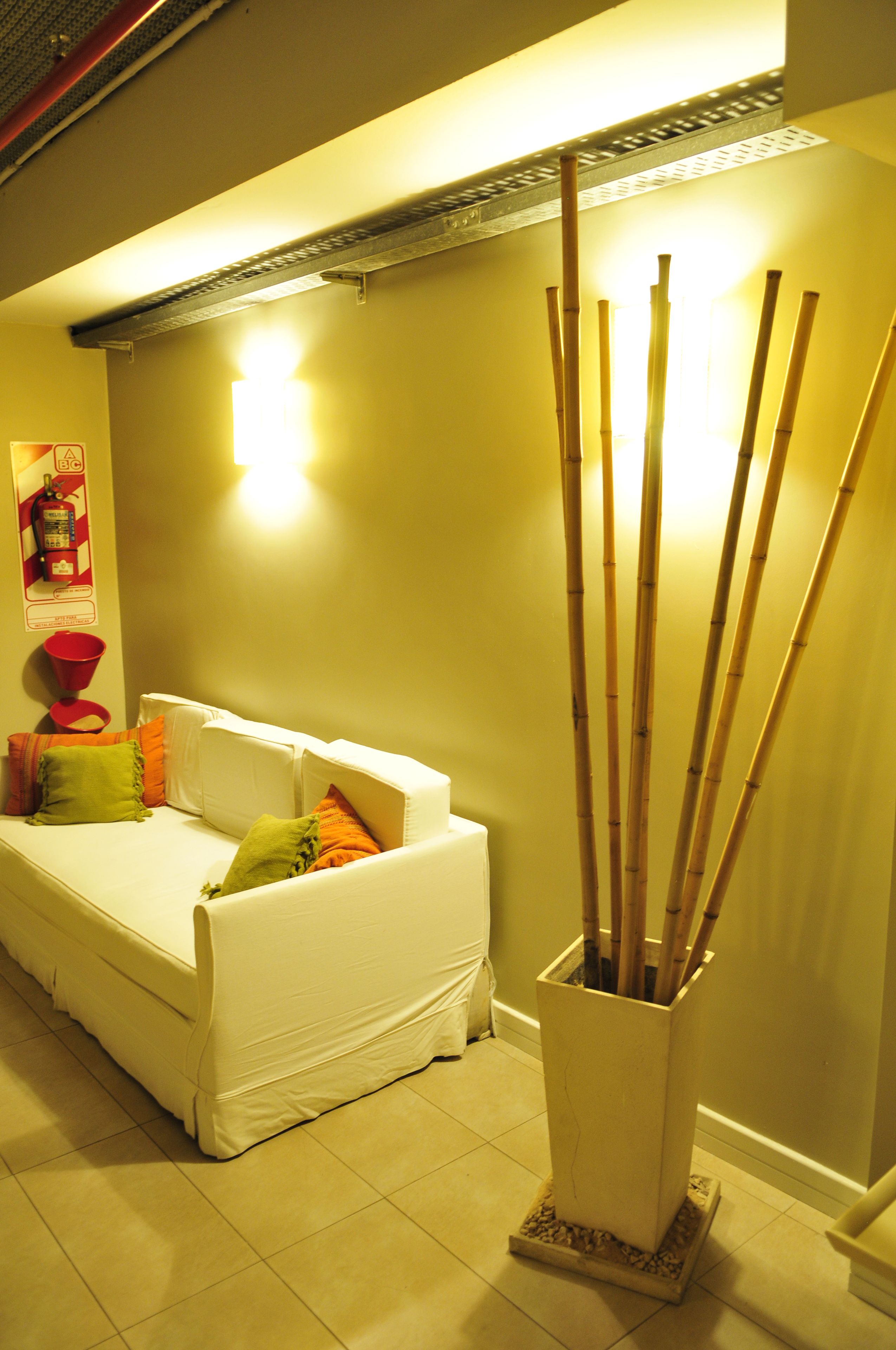 A room with a white sofa, a small table, and a tall vase with sticks.
