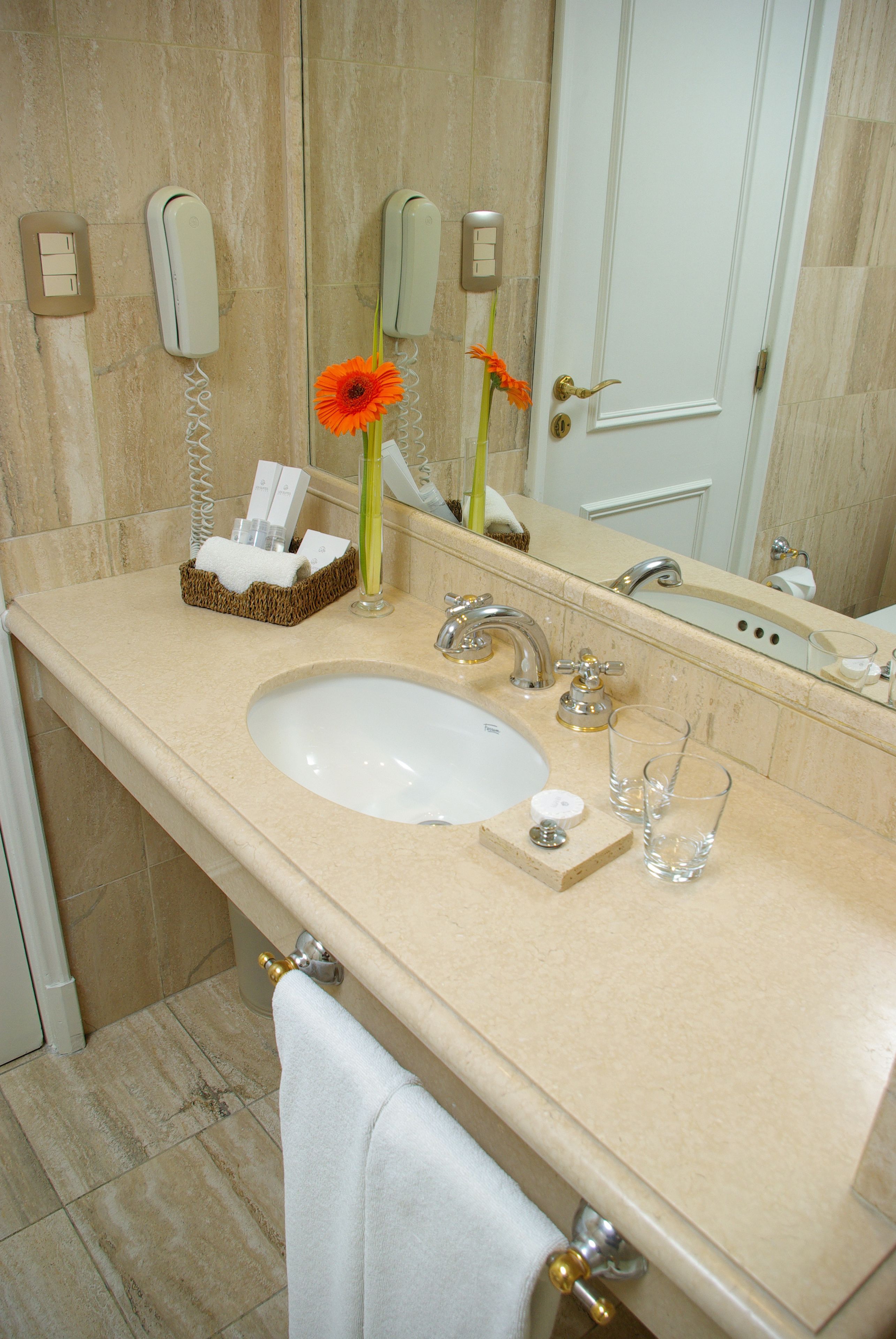 Un baño con lavabo, espejo y perchero para toallas.