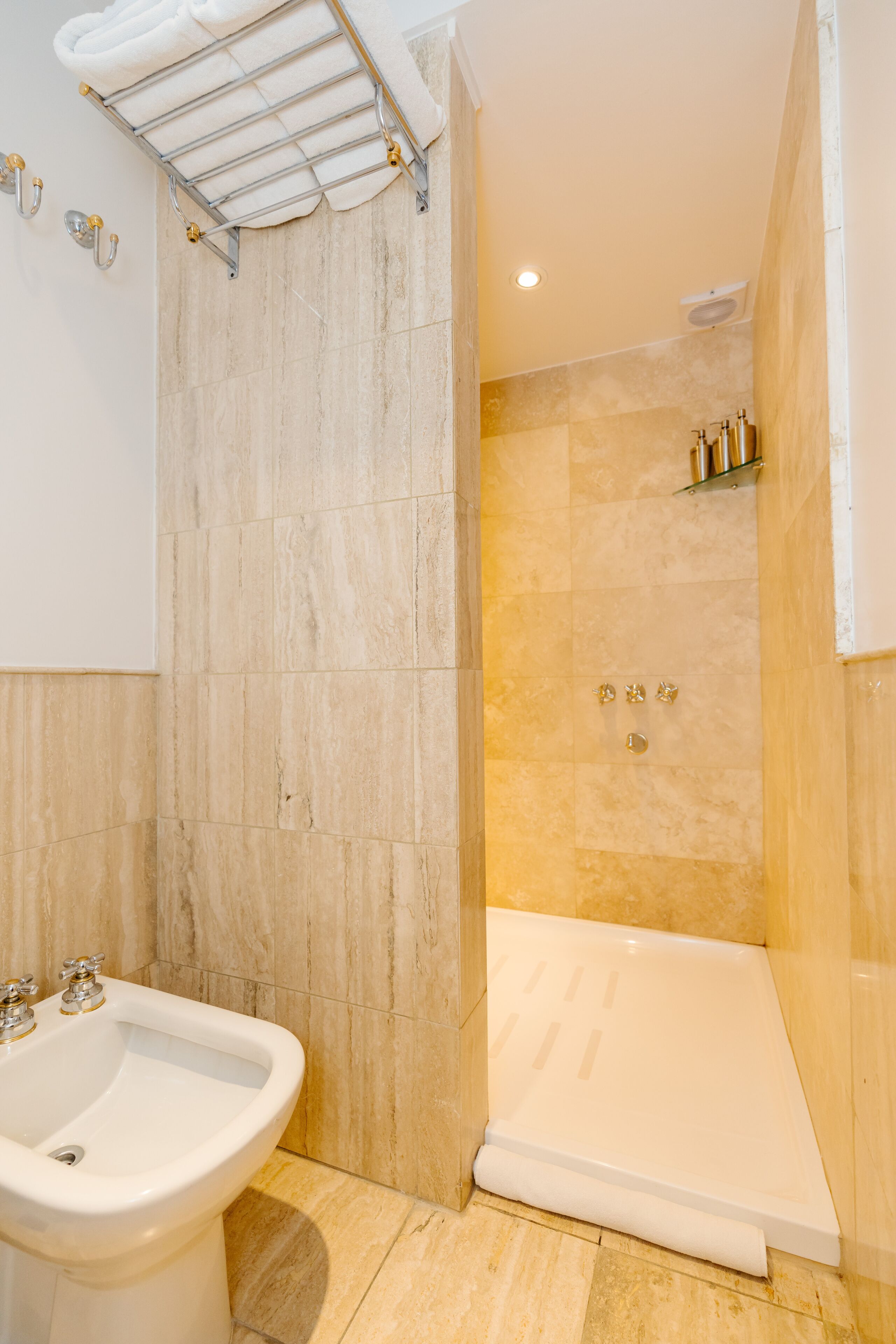 A bathroom with a sink, a shower, and a towel rack.