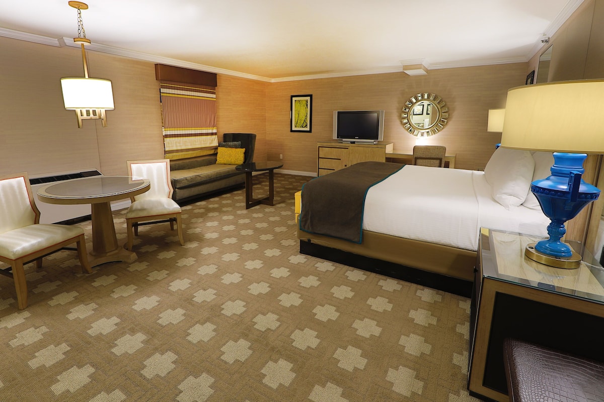 Ein Hotelzimmer mit Bett, Schreibtisch, Stuhl, Fernseher und Lampe.