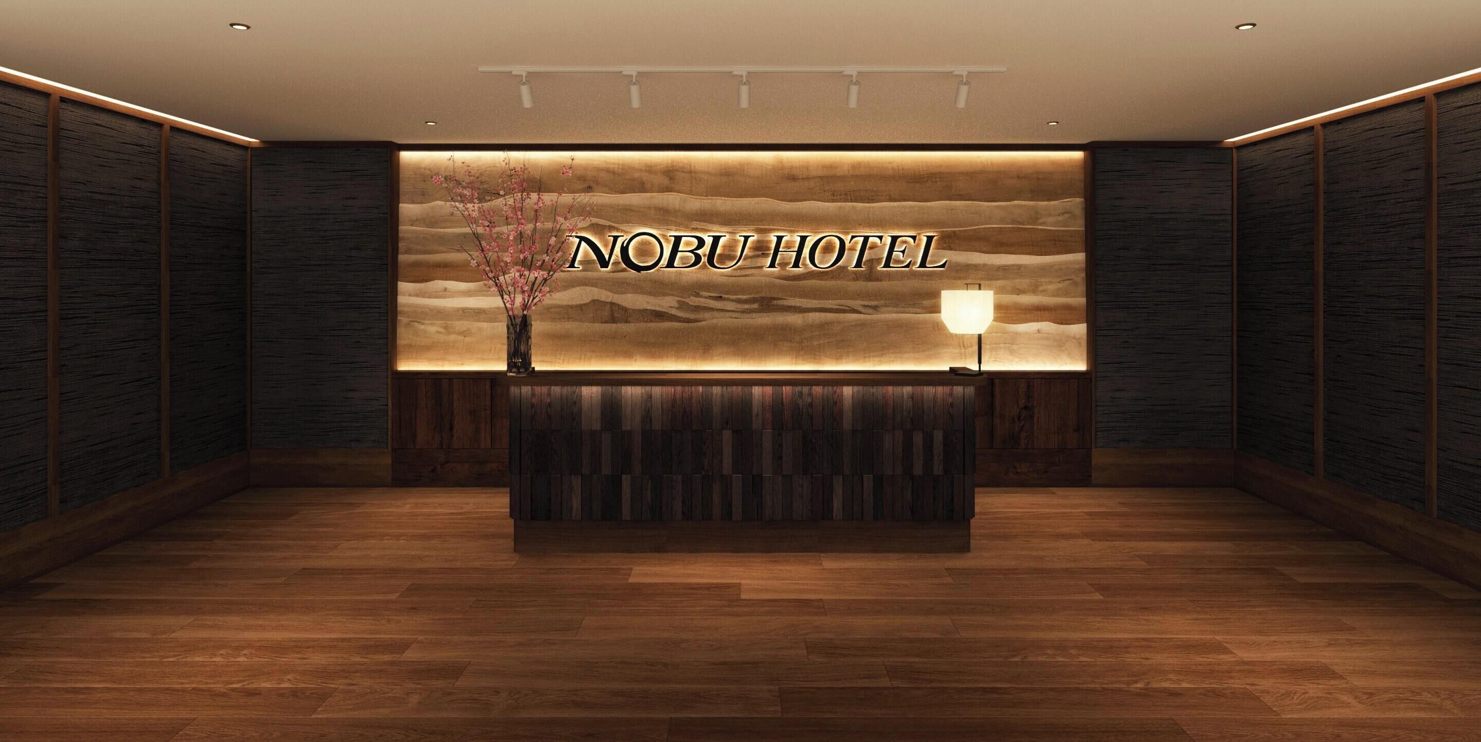 Un área de recepción con un mostrador de madera, un letrero en la pared que dice "Nobu Hotel" y un jarrón con flores rosadas.