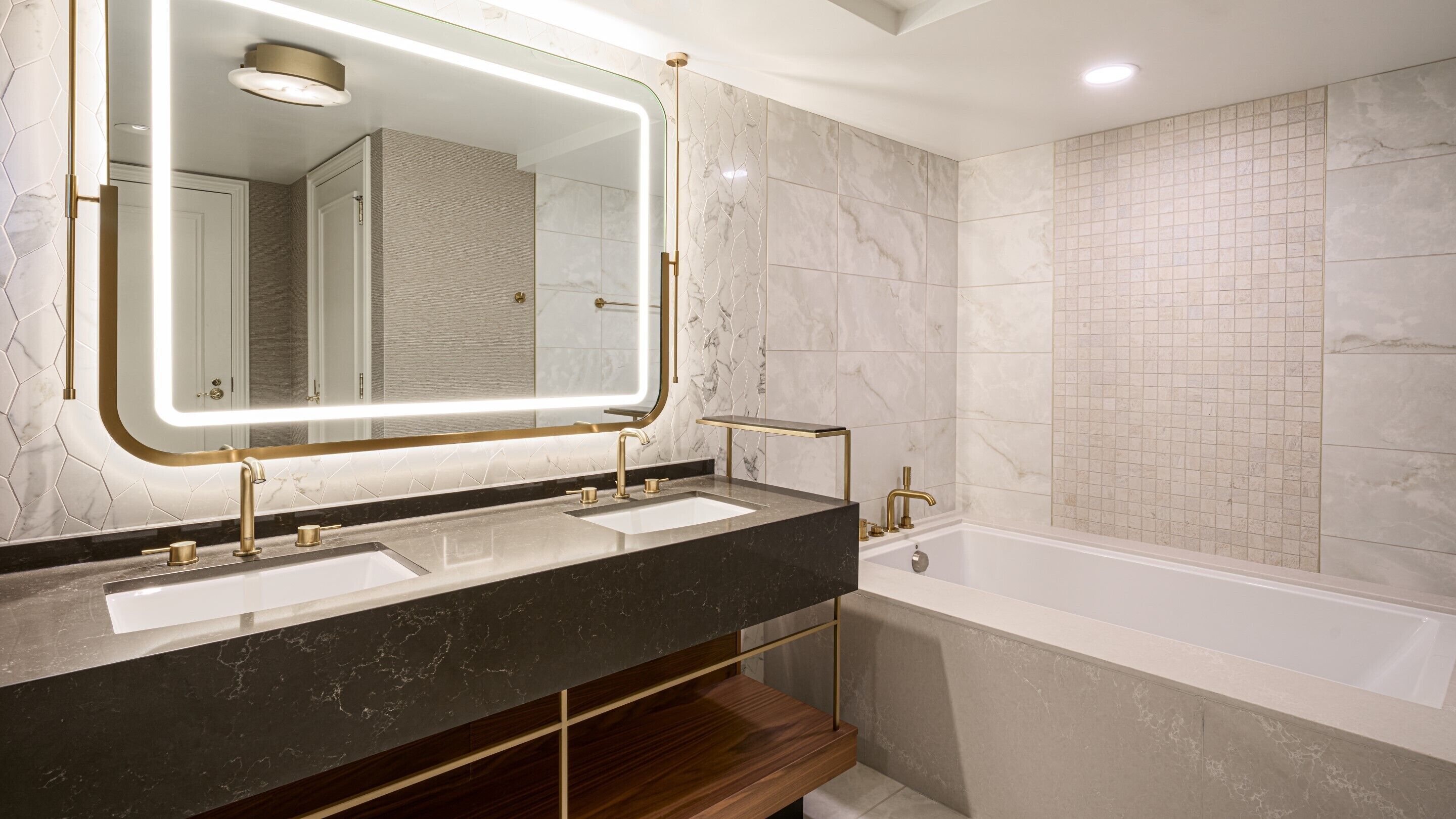 A modern bathroom with two sinks, a large mirror, and a bathtub.