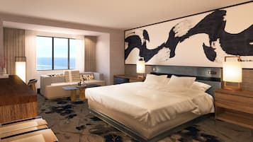 Ein Hotelzimmer mit einem großen Bett, einem Schreibtisch, einem Sofa und Meerblick.