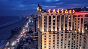 A high-rise hotel with a prominent 'Caesars' sign, featuring a classic architectural style with multiple windows and a corner tower.