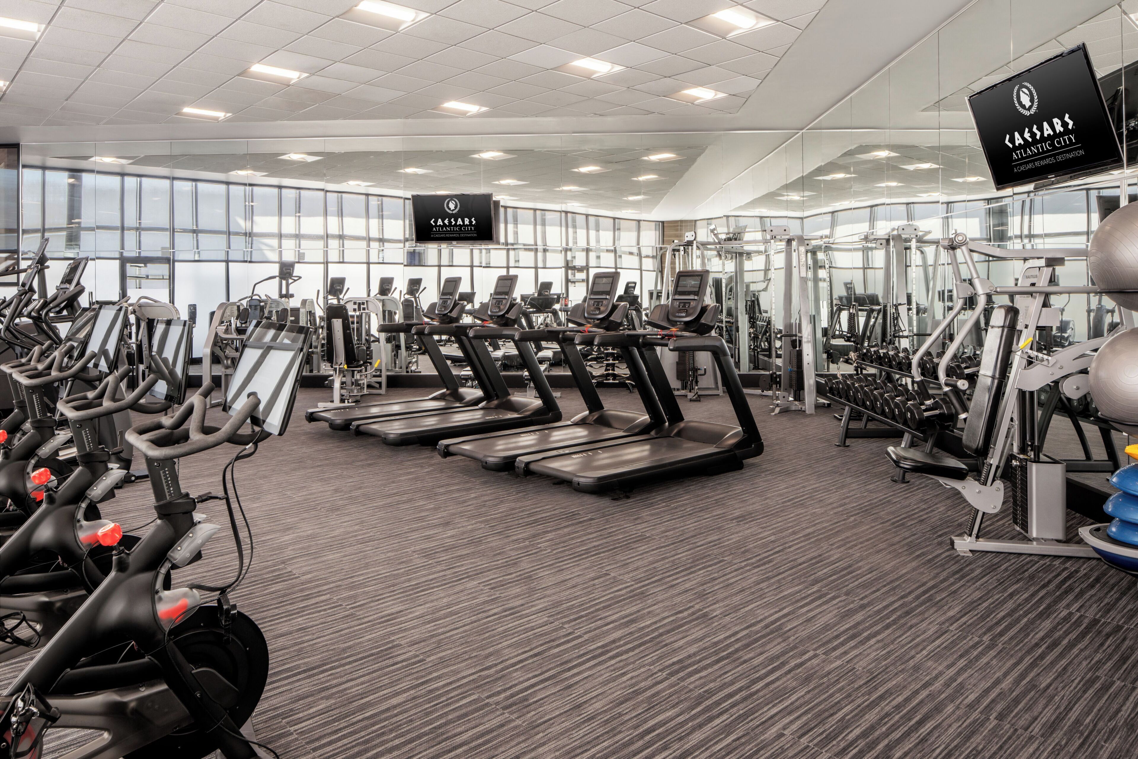 Un gimnasio con cintas de correr, bicicletas estáticas y máquinas de pesas.