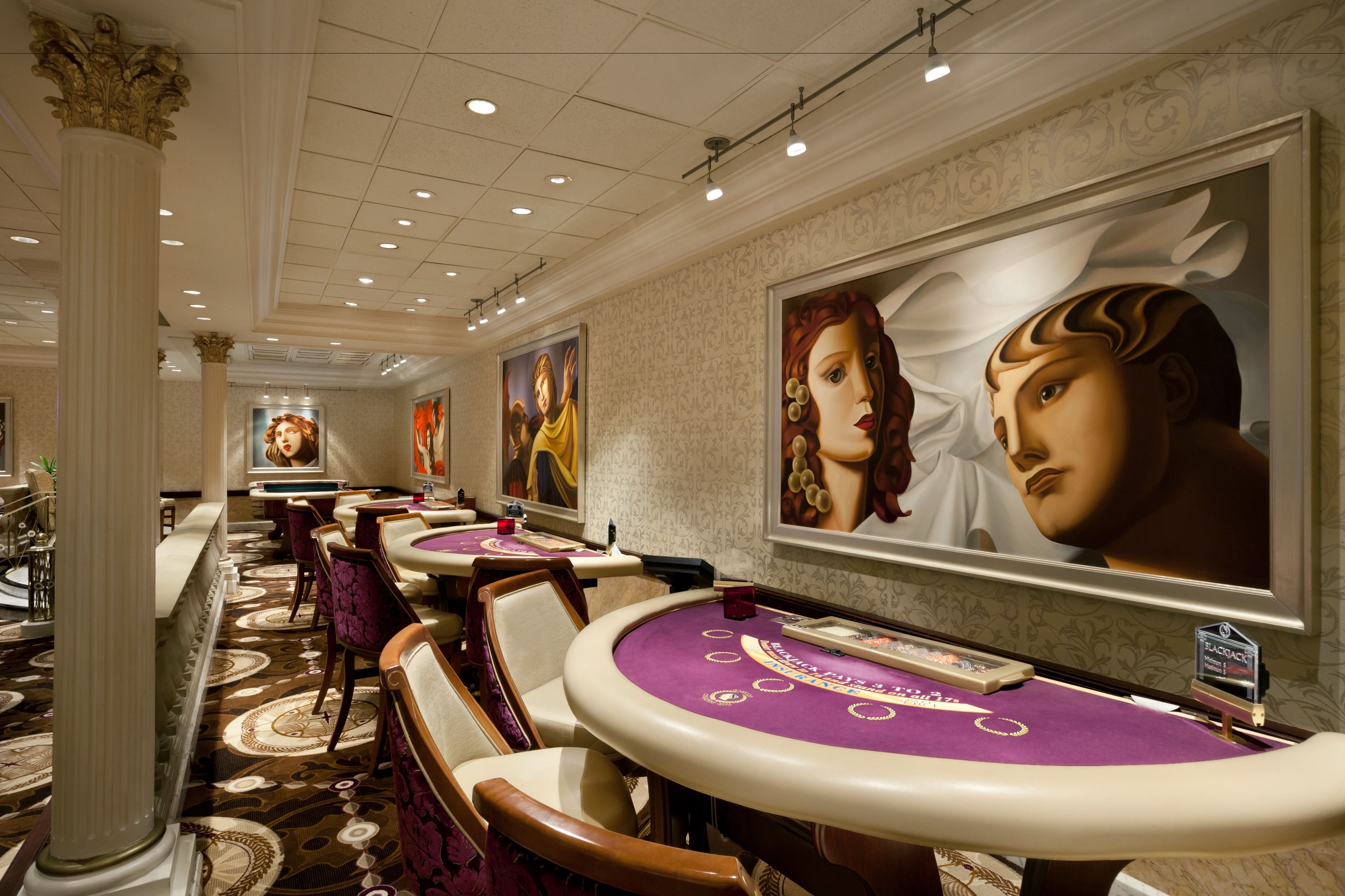 Un casino doté de plusieurs tables de blackjack, chacune recouverte d’un tapis violet et sur laquelle ne se trouve qu’une seule carte.