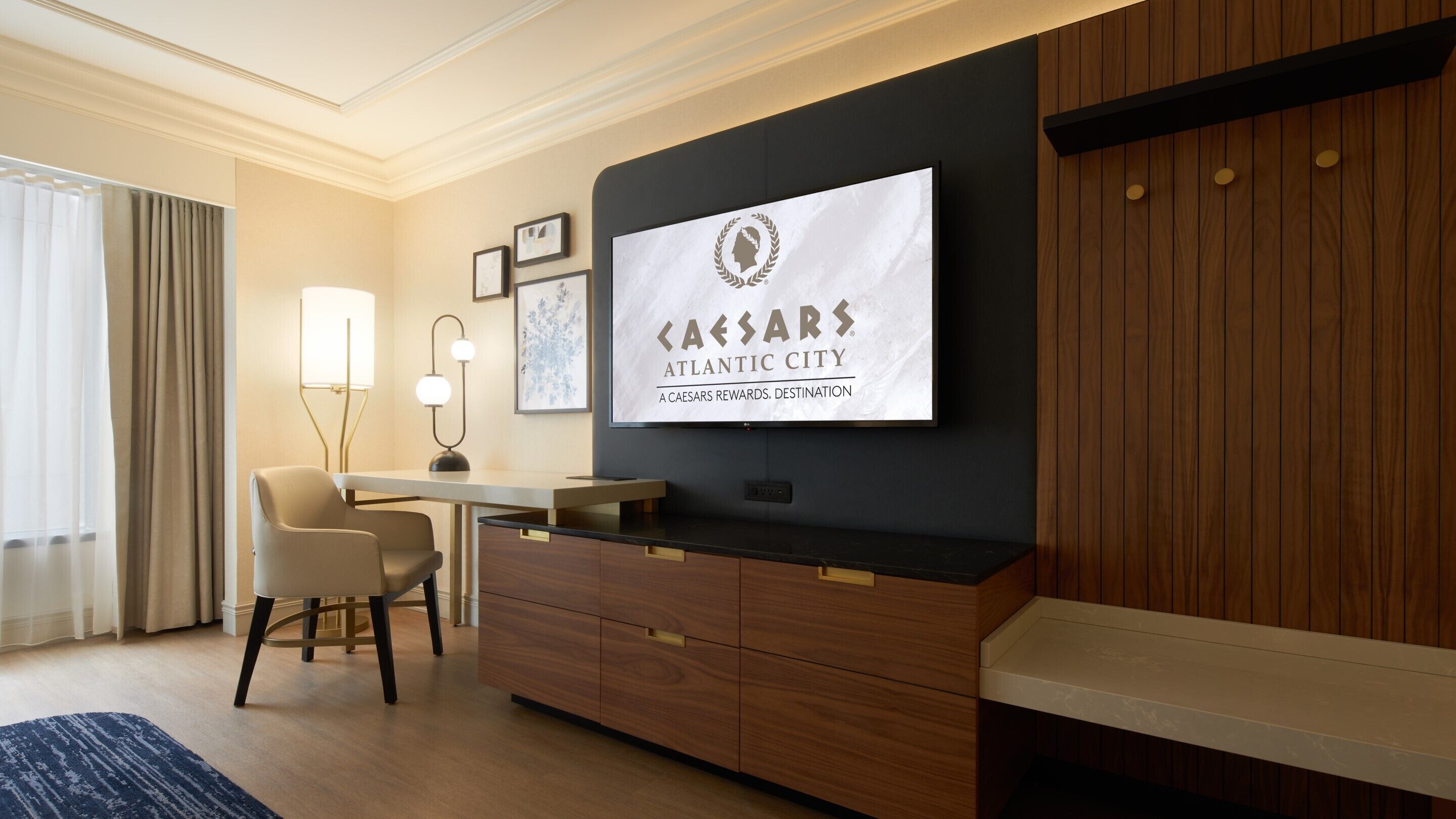 A hotel room with a desk, chair, and a large framed sign on the wall.