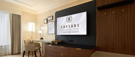 A hotel room with a desk, chair, and a large framed sign on the wall.