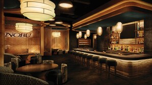 A bar area with a wooden bar counter, multiple stools, and hanging pendant lights.