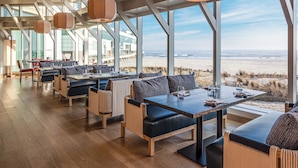 Un comedor espacioso con techos altos y amplias ventanas con vistas a la playa.