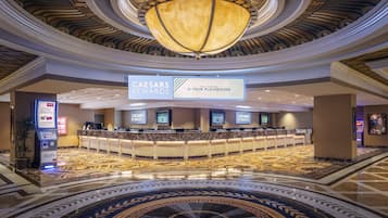 A hotel lobby with a central reception desk, a large chandelier, and a decorative circular floor pattern.