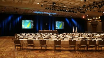 A conference room with a long table, chairs, a podium, and two screens displaying a map.