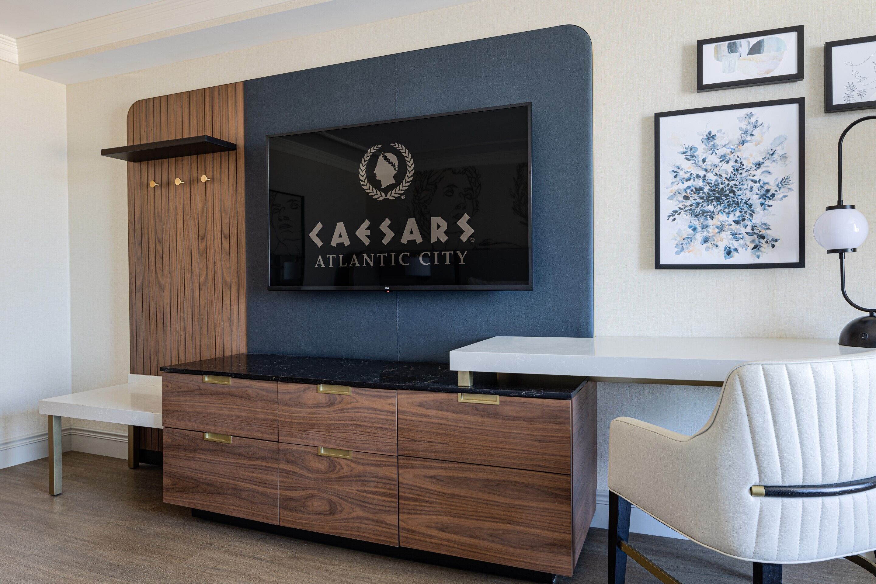 A modern kitchen with a wood and black countertop, a white chair, and a framed artwork above the counter.