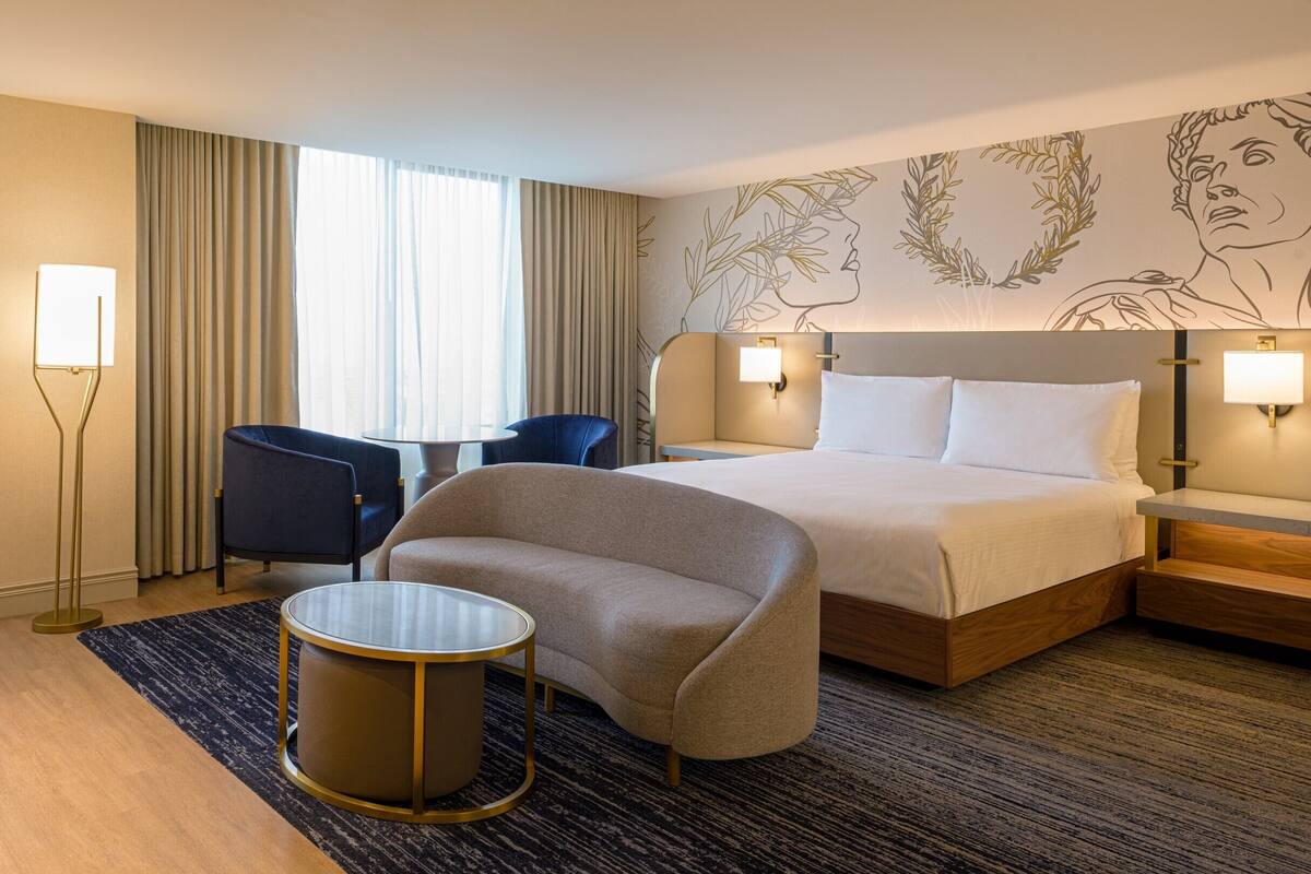 Ein Hotelzimmer mit einem Bett, zwei Stühlen, einem kleinen Tisch und einem Nachttisch.