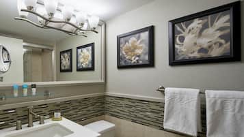 A bathroom with a large mirror, a sink, a toilet, and framed floral artwork on the wall.