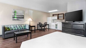 A hotel room with a bed, a sofa, a desk with a chair, a television, a microwave, and a refrigerator. - Extended Stay America Suites Houston Katy Freeway Energy Cor (Houston)
