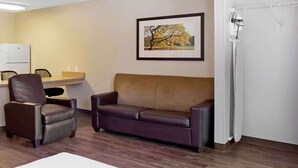 A room with a brown leather sofa, a brown leather chair, a small desk with a chair, a framed picture on the wall, and a white radiator. - Extended Stay America Suites Houston Katy Freeway Energy Cor (Houston)