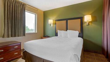Una habitación de hotel con una cama grande, dos lámparas de noche, un aparador de madera y una ventana con cortinas.