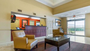 A lobby with a reception desk, two armchairs, a coffee table, and a large window with an exit sign. - Extended Stay America Select Suites - Houston - Sugar Land (Sugar Land)