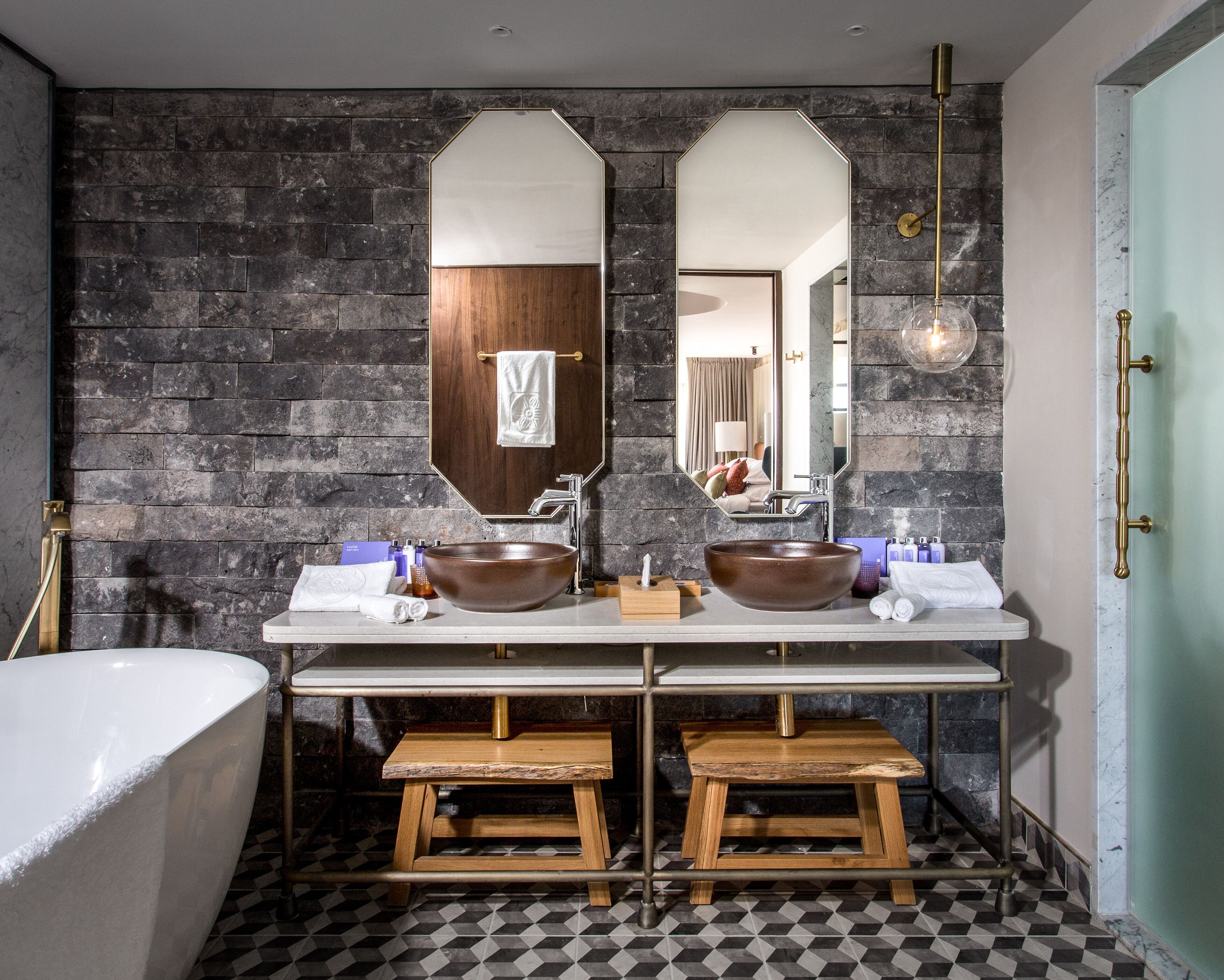 A bathroom with a large mirror, two sinks, a bathtub, and a checkered floor.