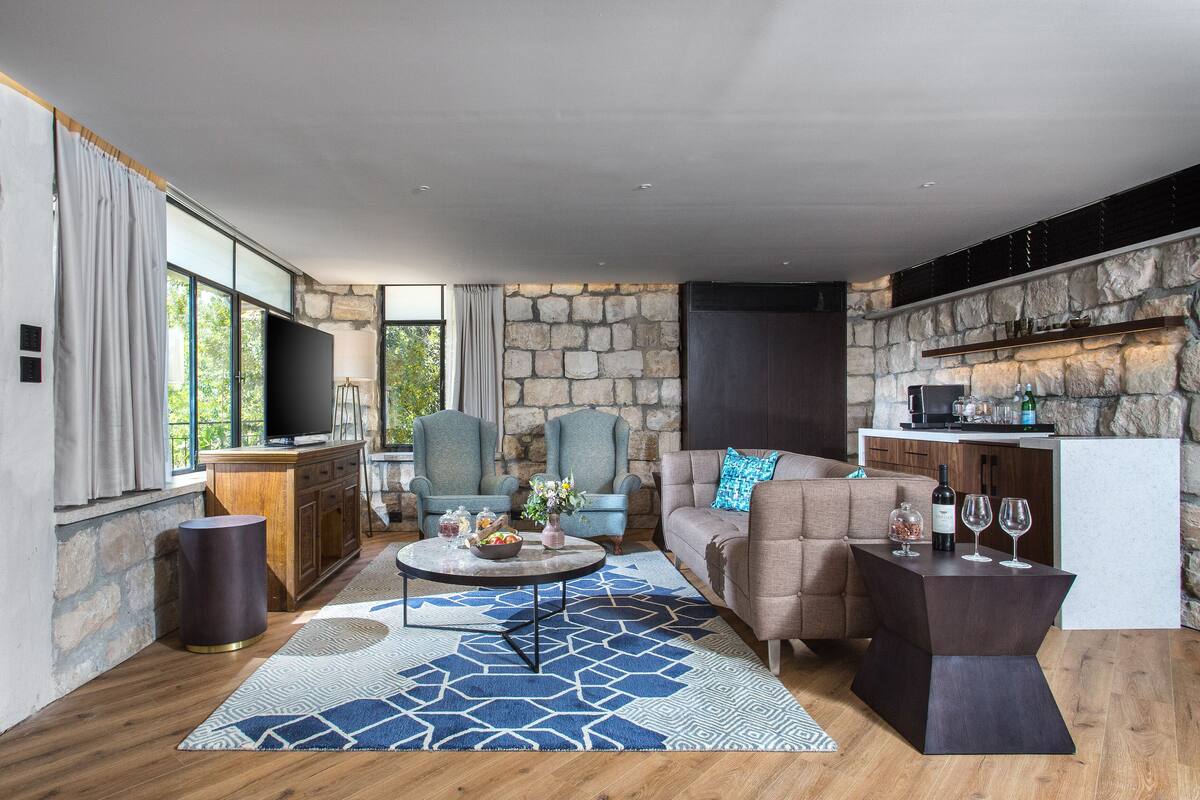 A modern living room with a stone wall, a large TV, and a cozy seating area with a coffee table.