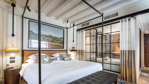 Una camera da letto moderna con un letto grande, una panca, un comodino e un quadro appeso al muro.