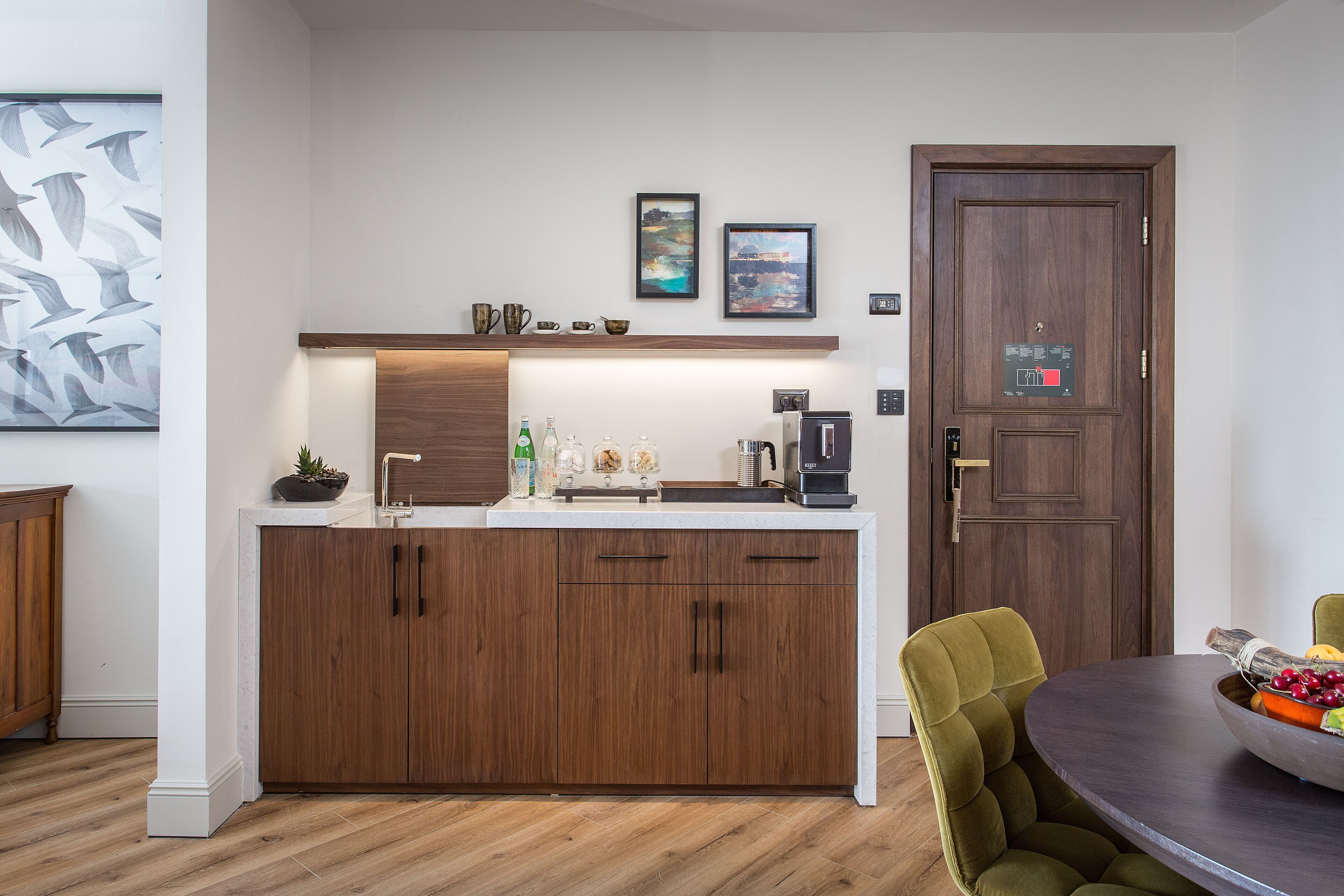 Una cocina moderna con armarios de madera, una encimera y una zona de comedor con mesa redonda y sillas verdes.