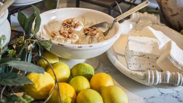 Un bol de nourriture avec une cuillère, une assiette de fromage et des citrons sur une table.