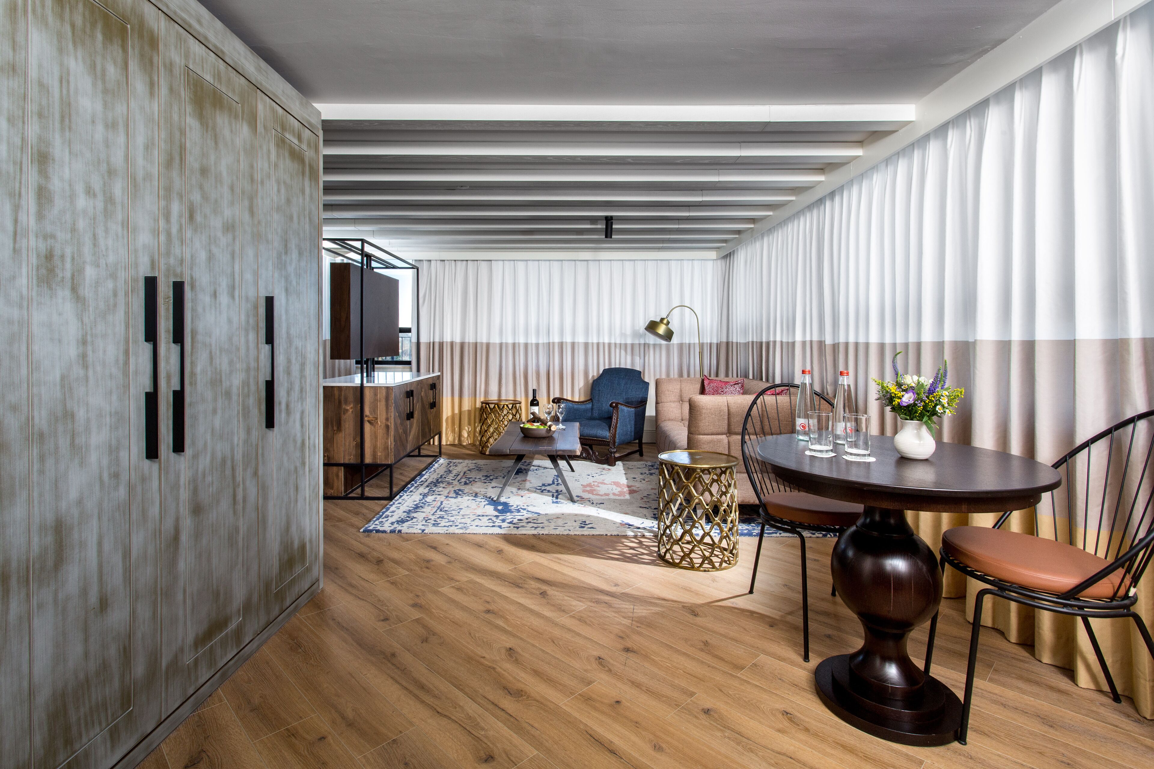 Una sala de estar moderna con piso de madera, una mesa de comedor redonda y un sofá.