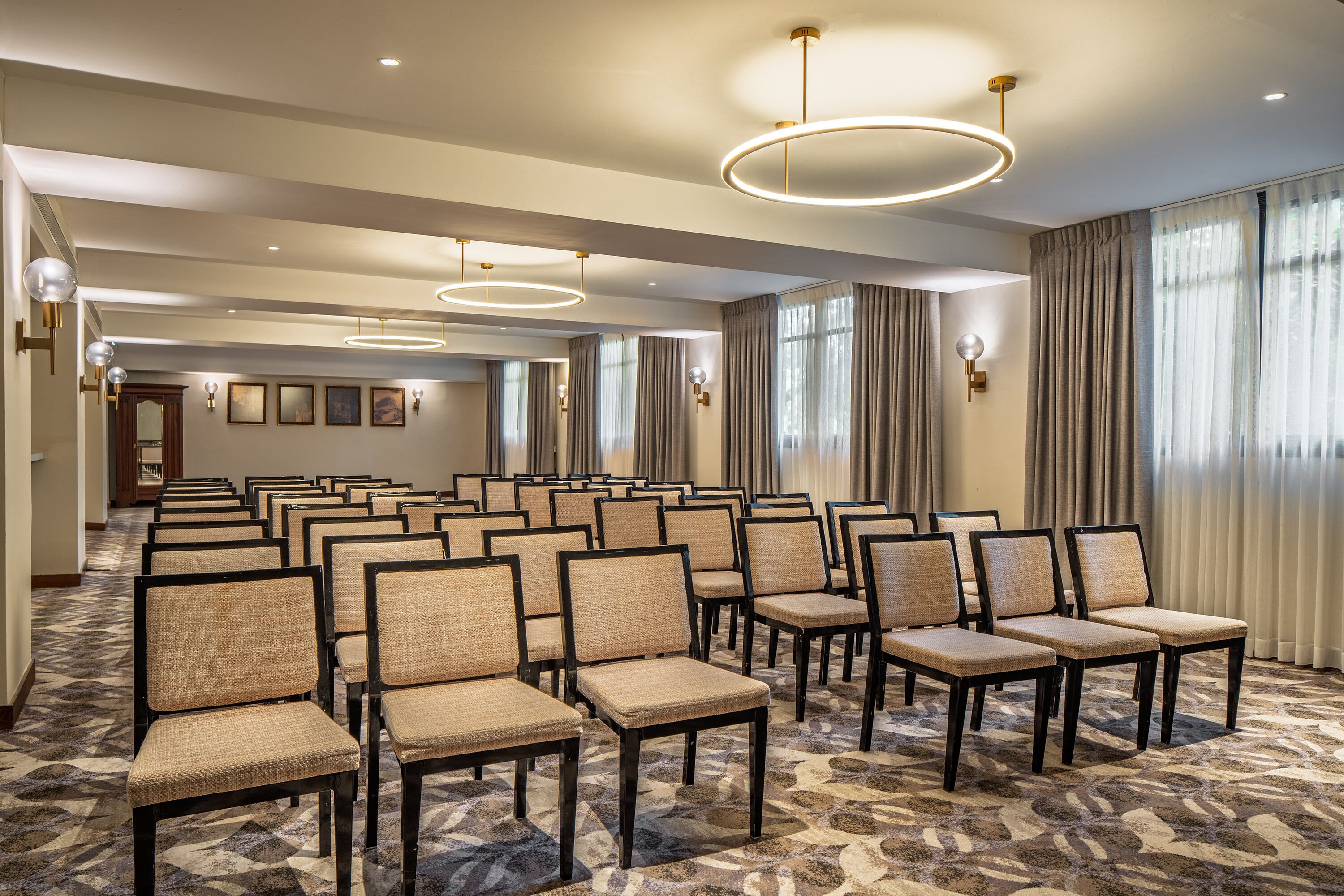 A conference room with rows of chairs, a patterned carpet, and modern lighting fixtures.