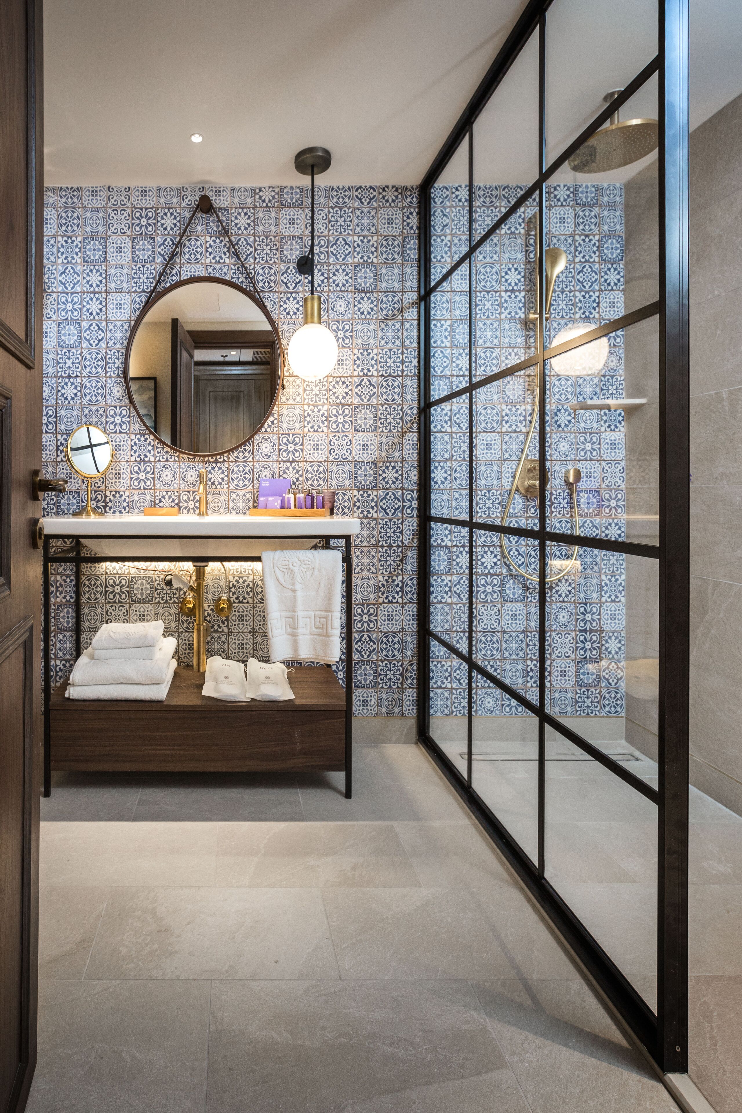 A bathroom with a vanity, a mirror, a towel rack, and a shower area.