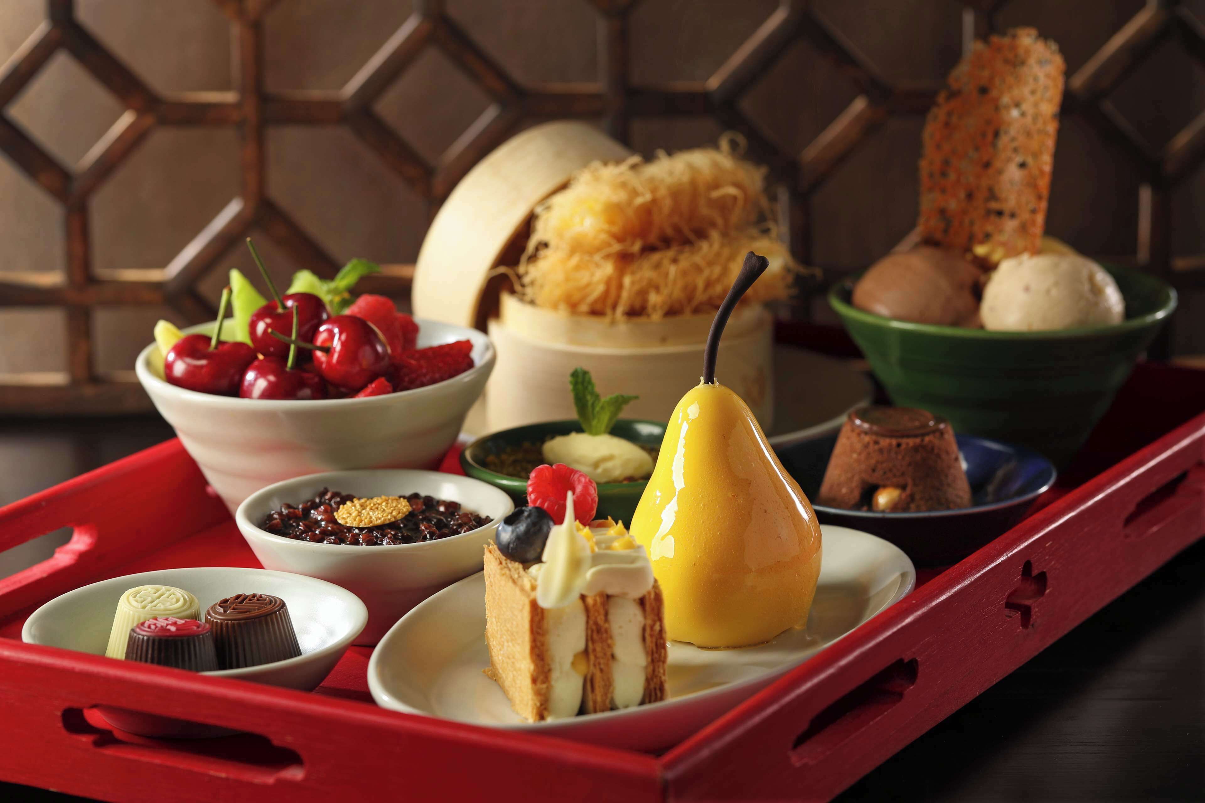 A tray with various desserts including a pear, a cake, and a chocolate dessert.