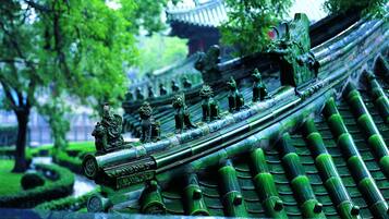 A traditional architectural structure with intricate carvings and statues, surrounded by lush greenery.