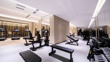 A modern gym with treadmills, weight machines, and benches.