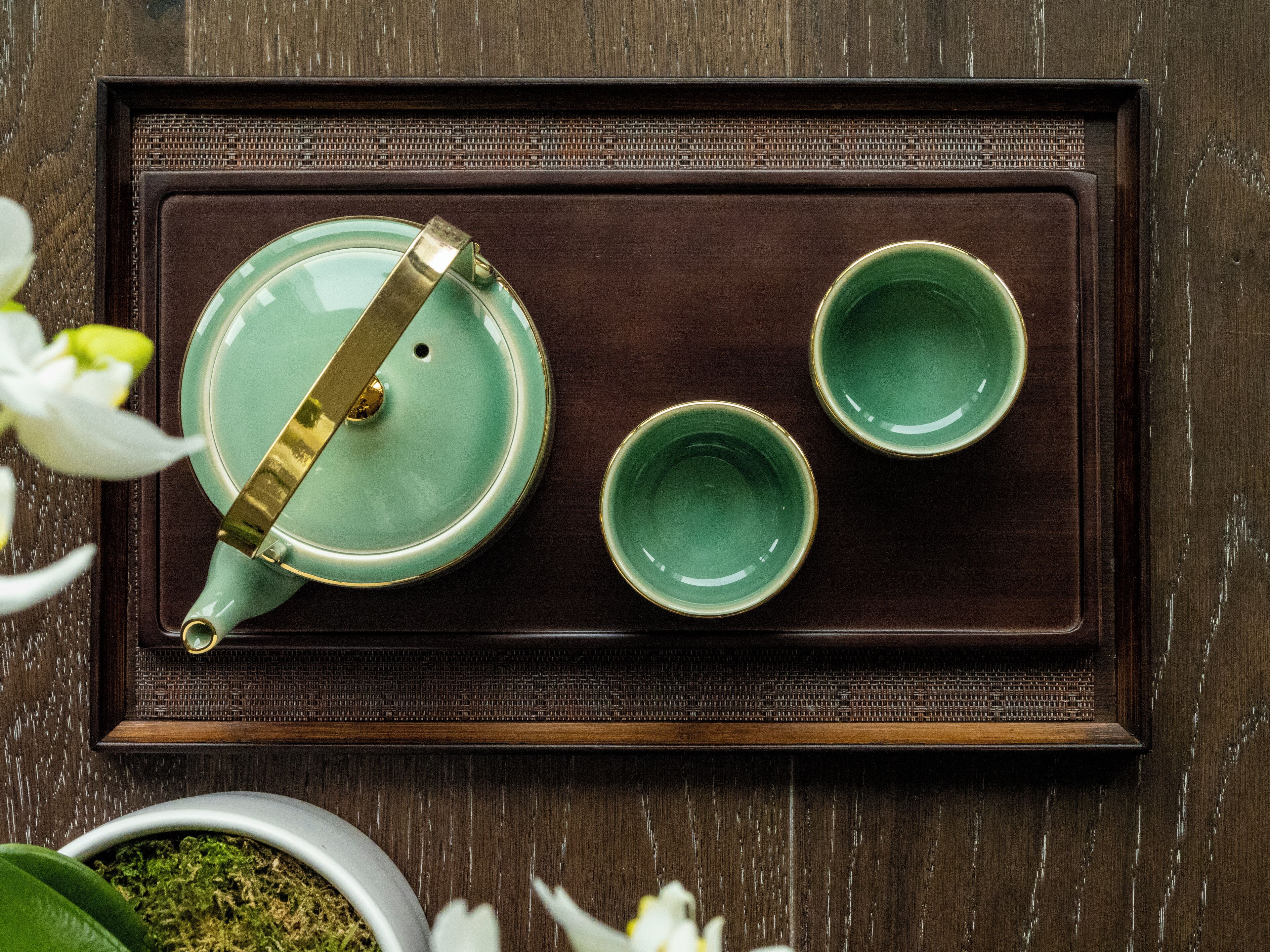 A tray with a teapot and two cups on a wooden surface.