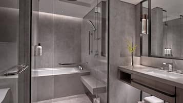A modern bathroom with a glass-enclosed shower, a large mirror, and a vanity with a sink and towel rack.