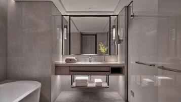 A modern bathroom with a freestanding bathtub, a large mirror, and a minimalist sink area.