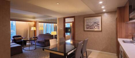 A hotel room with a dining area, a sofa, a table, and a kitchen area.