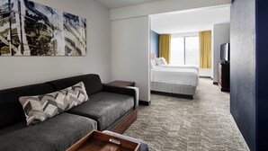 Une chambre d’hôtel avec un canapé, un lit, une télévision et un tableau au mur.