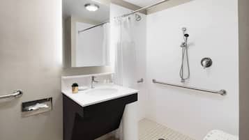 A modern bathroom with a white sink, a mirror, a shower with a handheld showerhead, and a grab bar.