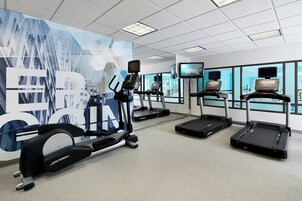 Un gimnasio con cintas de correr, bicicletas estáticas y un gran mural motivacional.