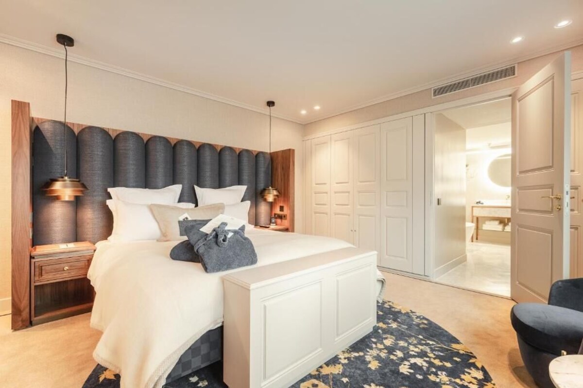 A bedroom with a bed, bedside tables, a wardrobe, and a bathroom visible through an open door.