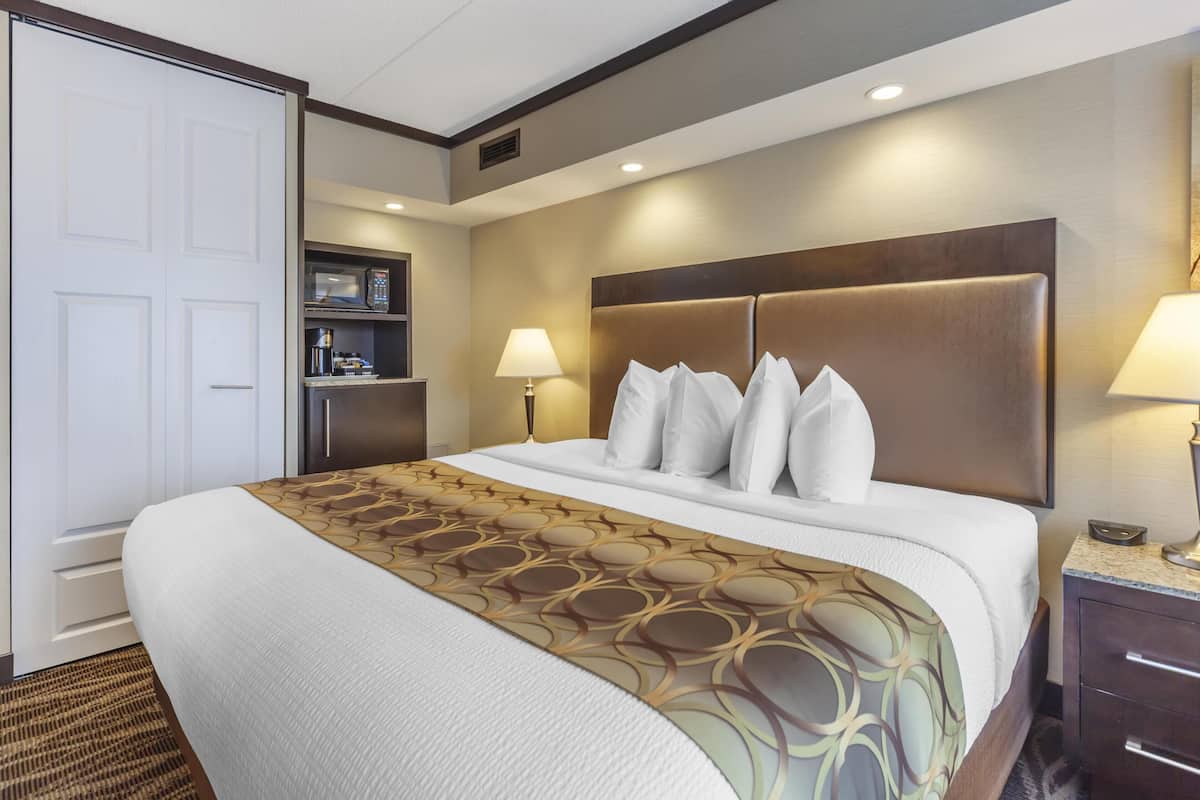 A hotel room with a large bed, two bedside lamps, a nightstand, and a wardrobe.