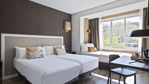 Ein Hotelzimmer mit zwei Betten, einem Schreibtisch und einem Fenster mit Vorhängen.