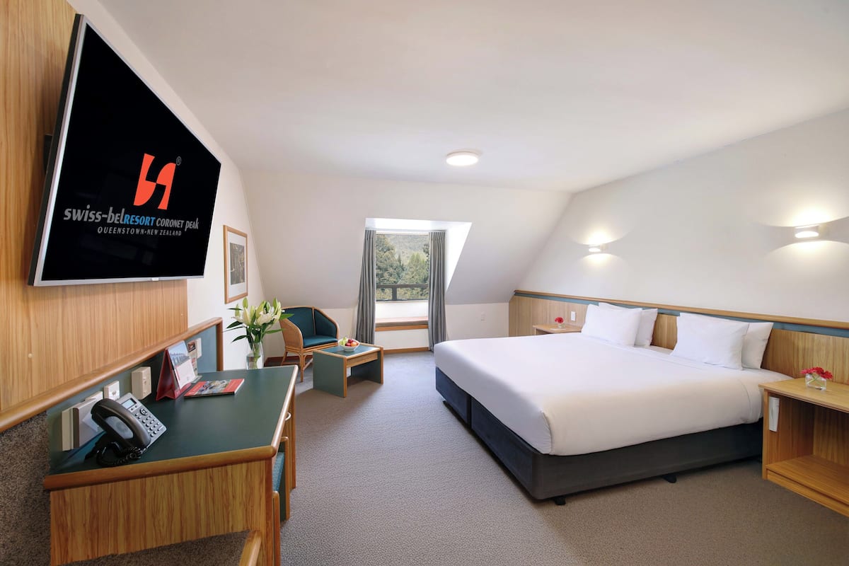 Ein Hotelzimmer mit Bett, Schreibtisch, Stuhl und Fernseher, der den Namen des Hotels anzeigt.