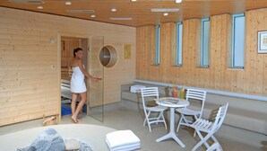 A modern spa room with wooden walls, a sauna, and a seating area with a table and chairs. - Hotel am Rosengarten (Bad Wimpfen)