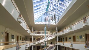 A multi-level atrium with a central spiral staircase, multiple balconies, and a glass ceiling allowing natural light. - Hotel am Rosengarten (Bad Wimpfen)