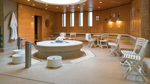 A sauna room with wooden walls, a central circular seating area, and multiple benches. - Hotel am Rosengarten (Bad Wimpfen)