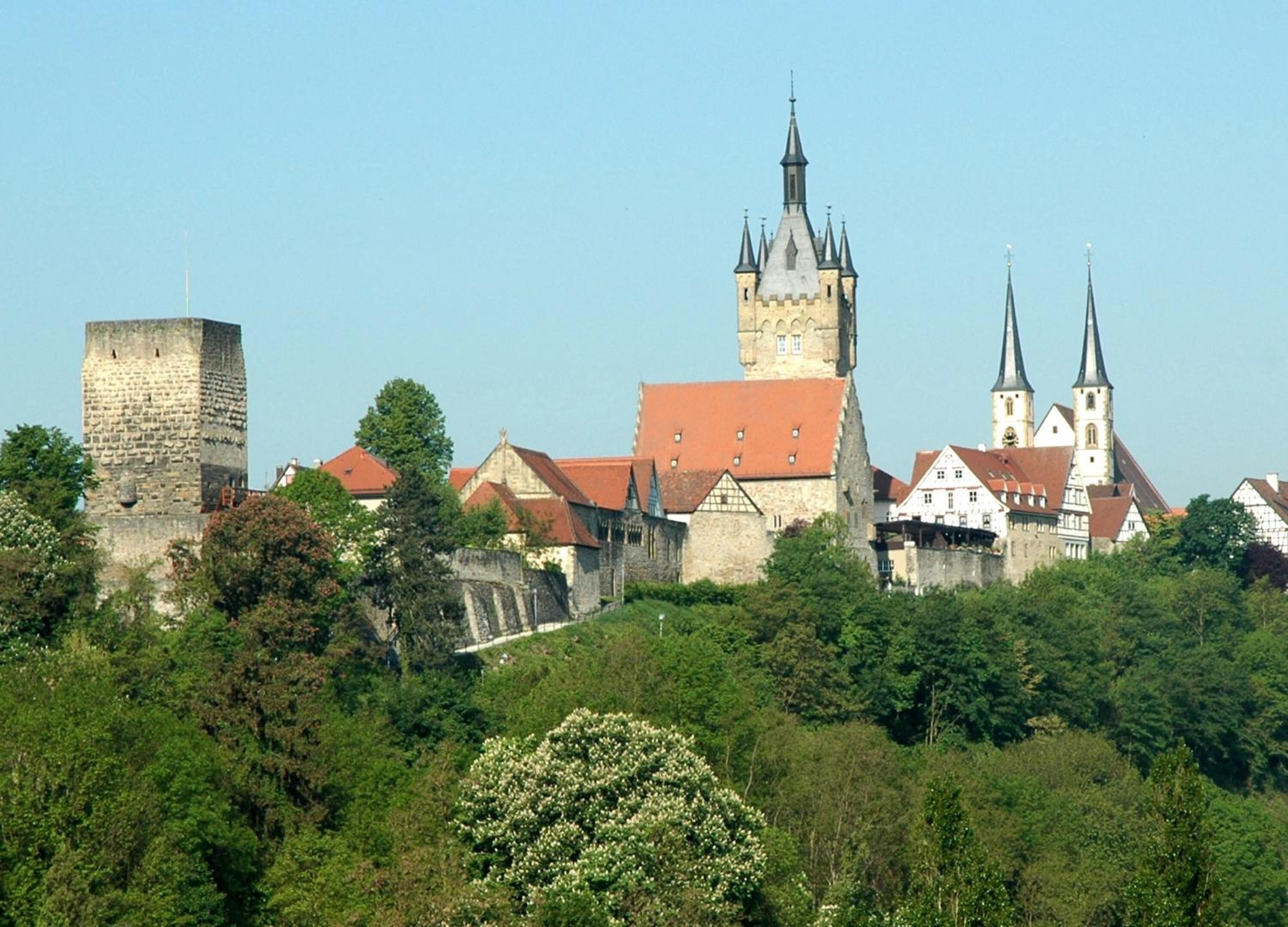 Eine historische Stadt mit einem markanten Turm und einer Kirche mit zwei Kirchtürmen.
